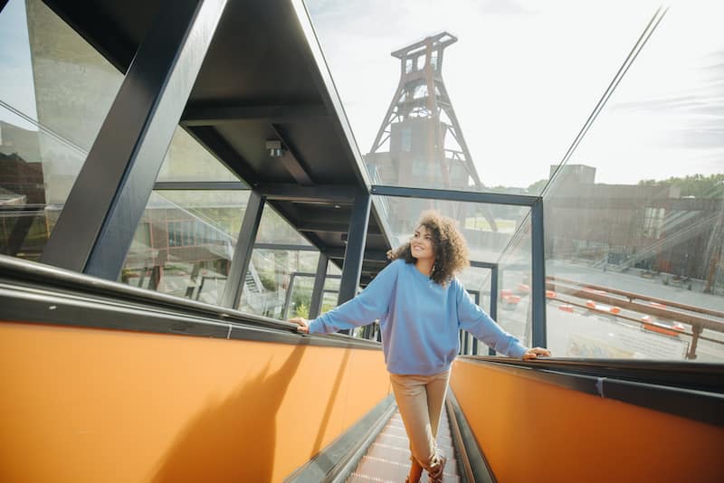 Esen žena na pokretnim stepenicama u Zollverein u UNESCO svetska baština